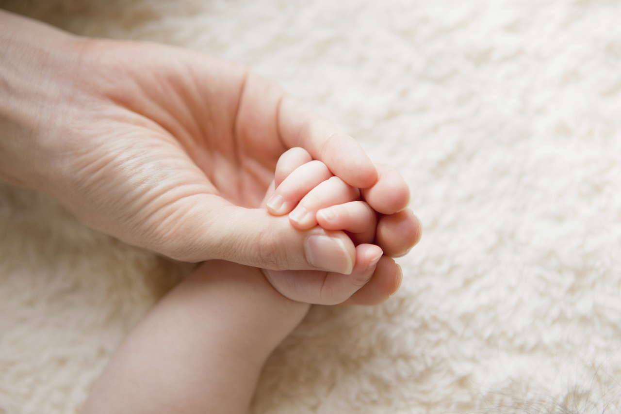 赤ちゃんの手を握る大人の手元
