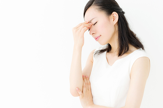 眉間を押さえる女性