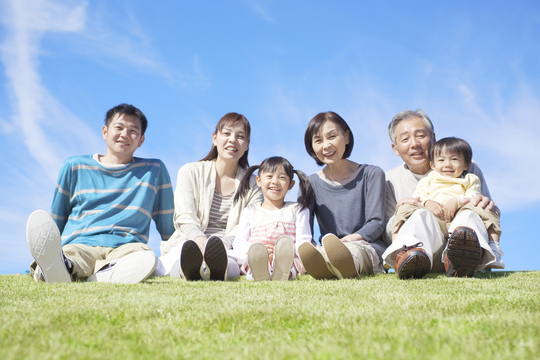 芝生に座る三世帯家族