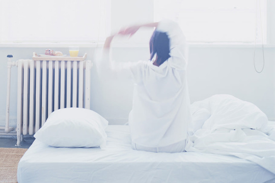 寝起きに伸びをする女性